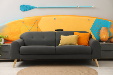 214510973 sup board paddle and stylish sofa in living room interior design